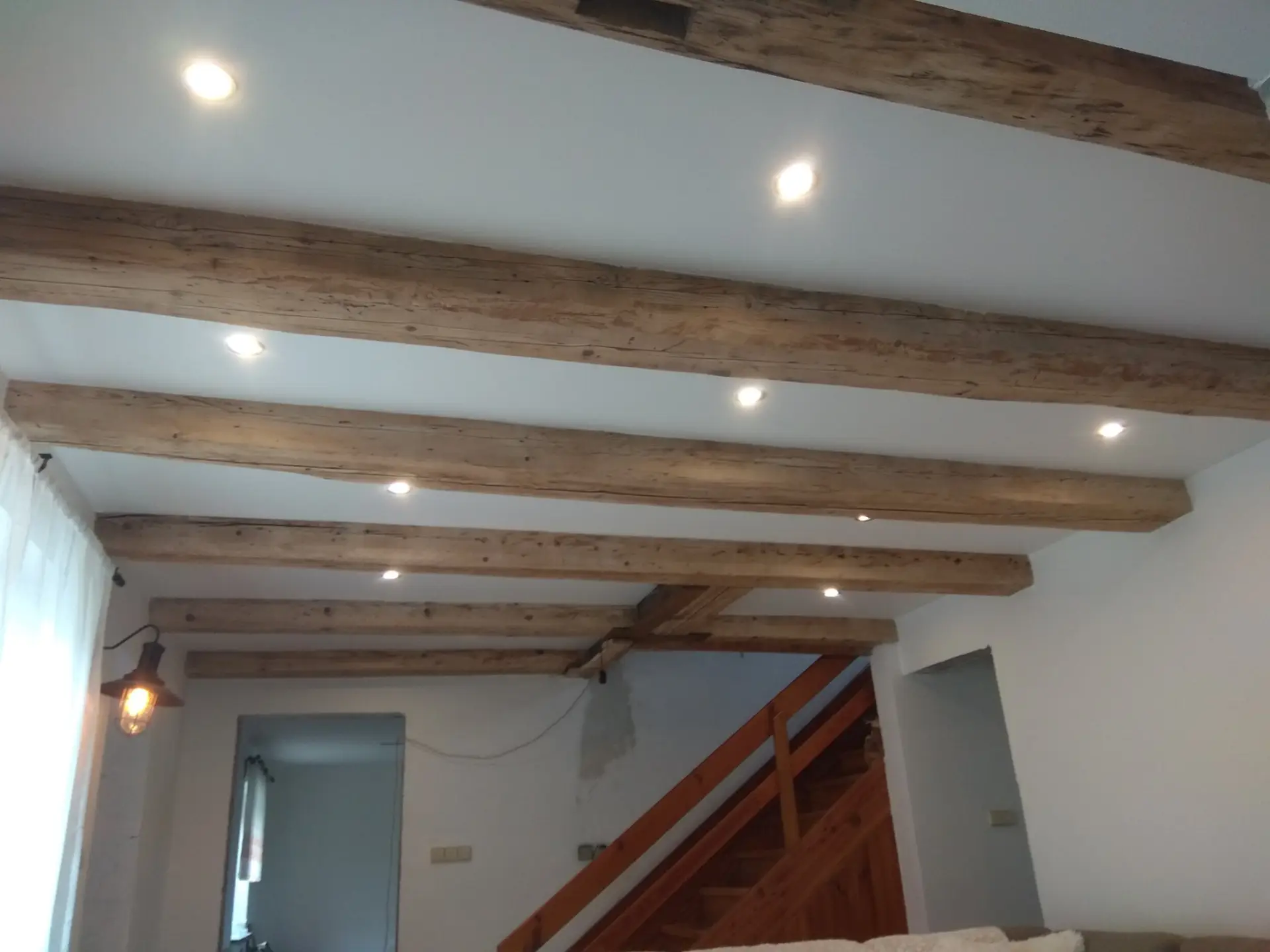 Interiérové osvětlení, bodovky a dřevěné trámy na schodišti