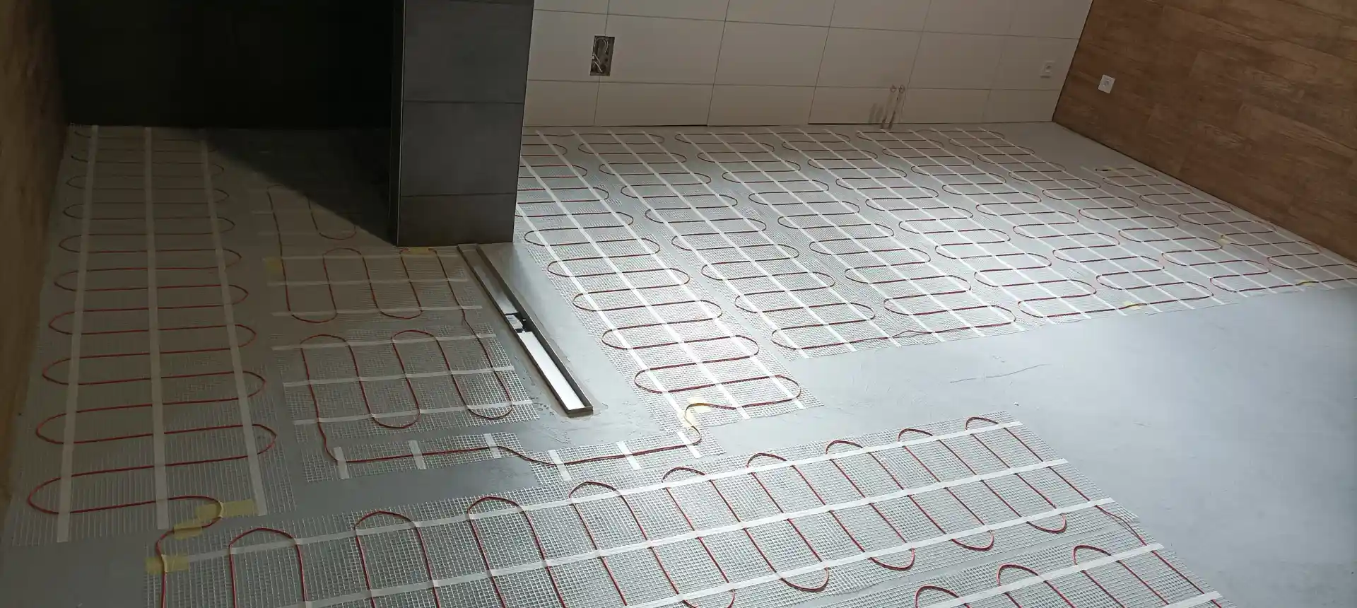 Instalace elektrického podlahového vytápění Fenix v koupelně u sprchového žlabu.