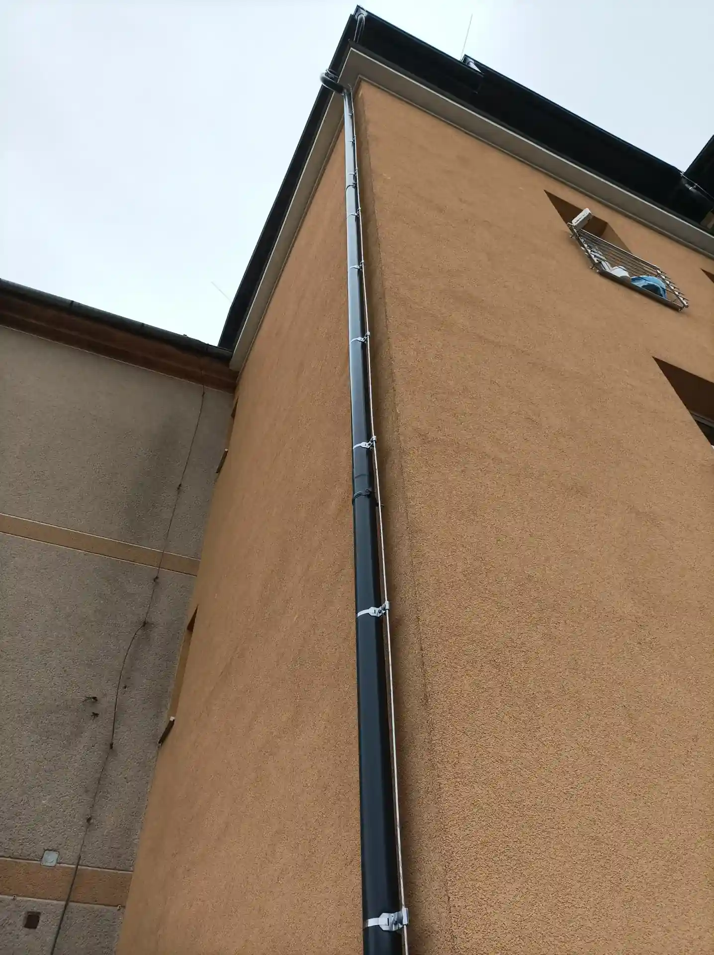 Svislé vedení svodu hromosvodu po fasádě bytového domu