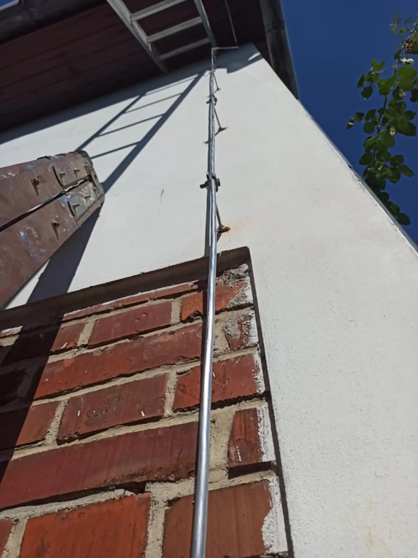 Detailní pohled na vedení svodu hromosvodu po fasádě nad cihlovým obkladem