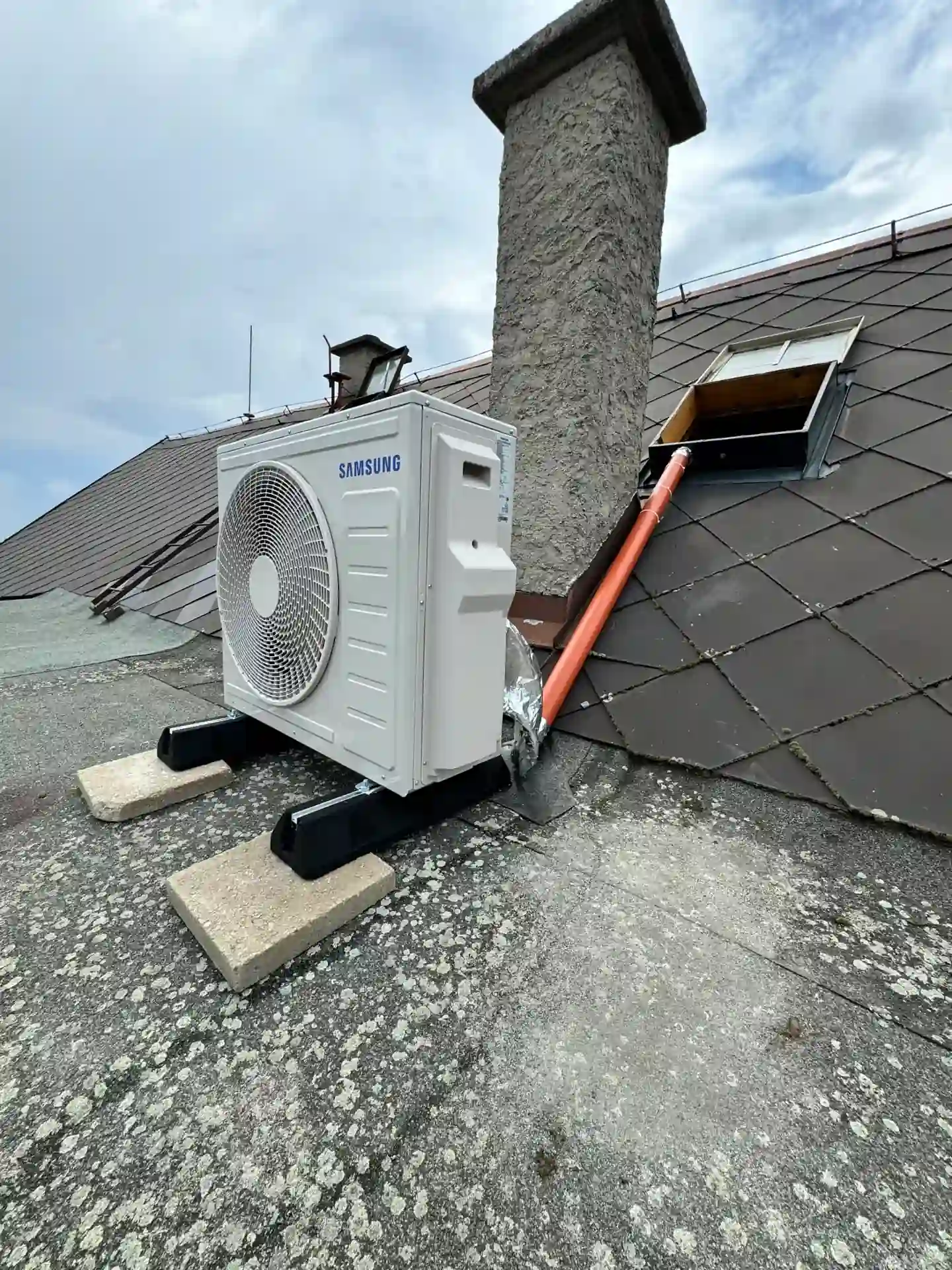 Instalace venkovní klimatizace na střeše rodinného domu u komína