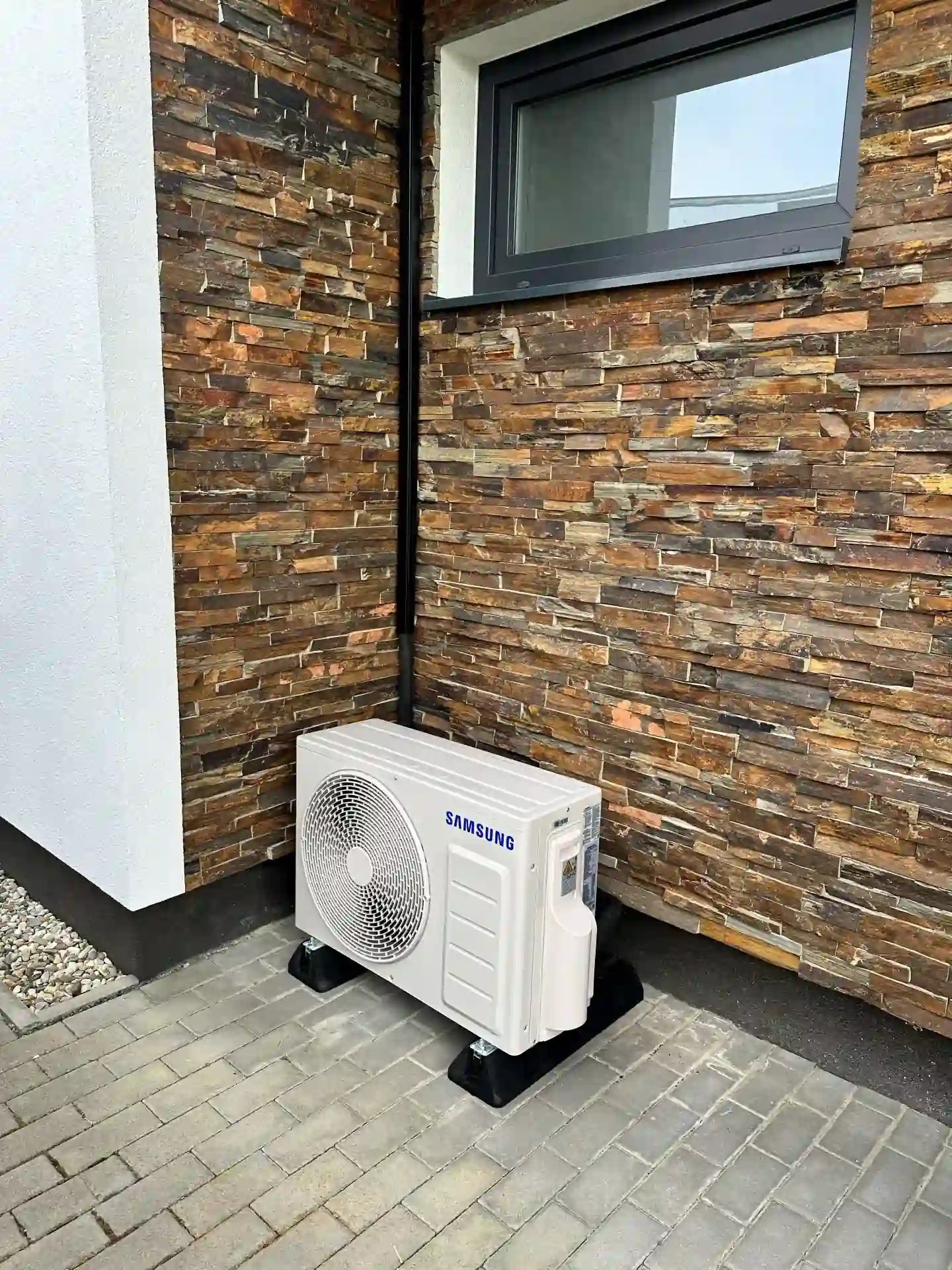 Venkovní klimatizace Samsung instalovaná u domu s kamenným obkladem