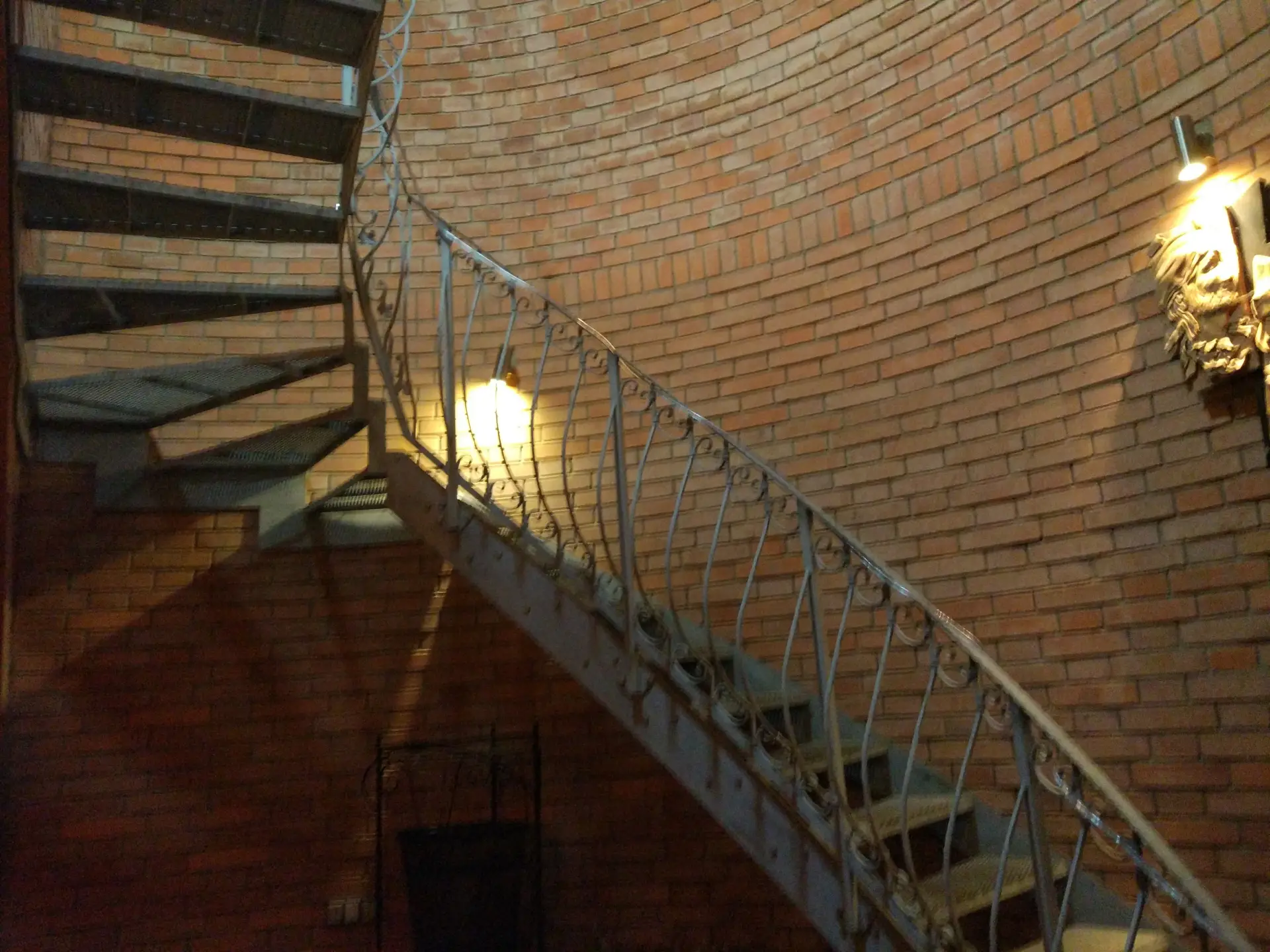 Stylové osvětlení točitého schodiště u cihlové stěny