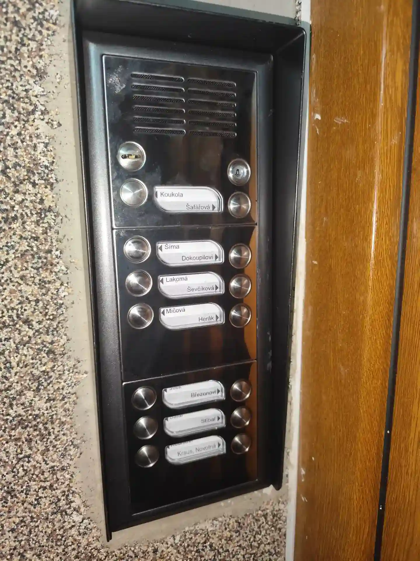 Detailní pohled na instalovanou venkovní jednotku domovního interkomu.