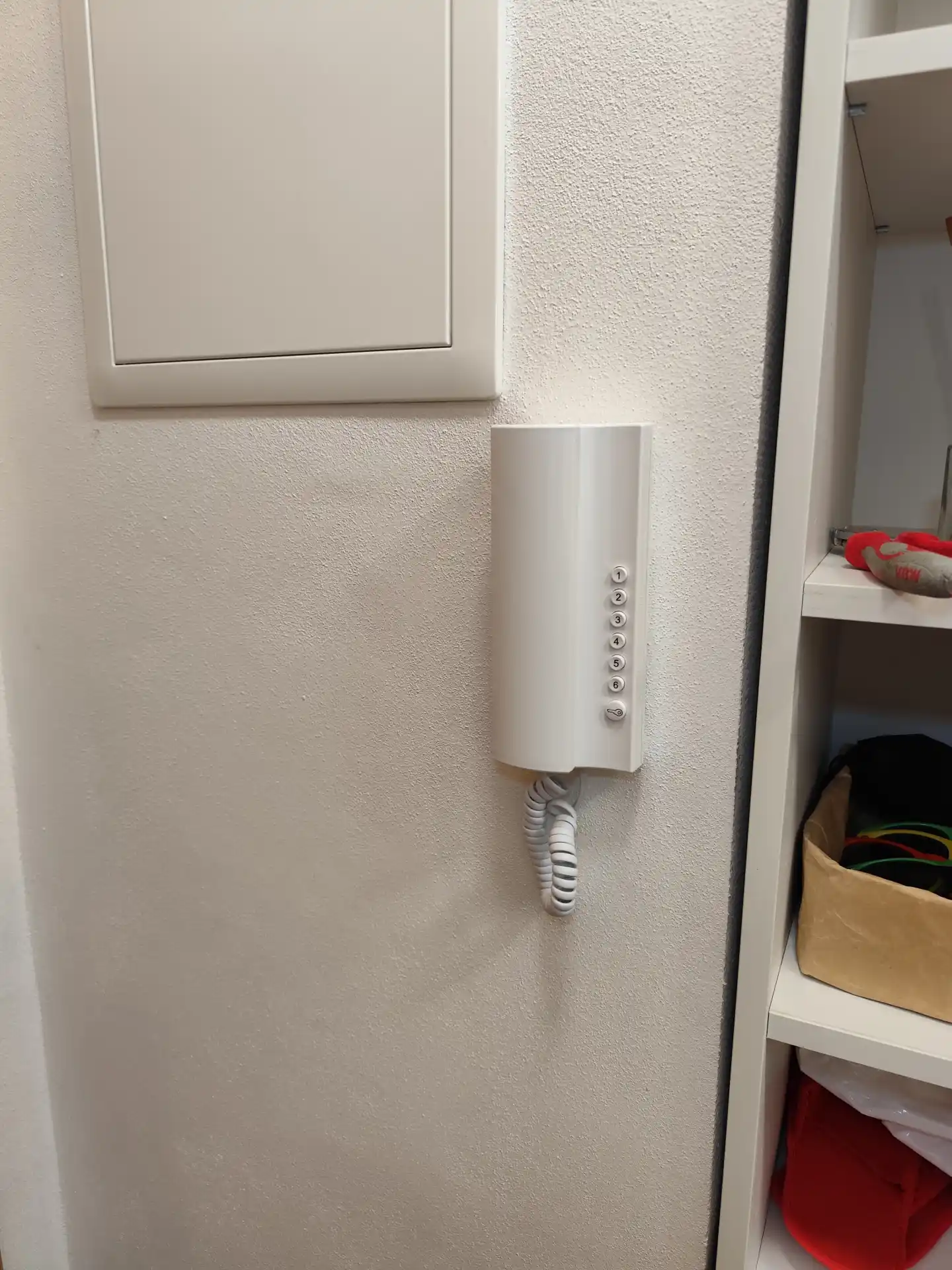 Nové vnitřní sluchátko domovního telefonu v moderním bílém designu.