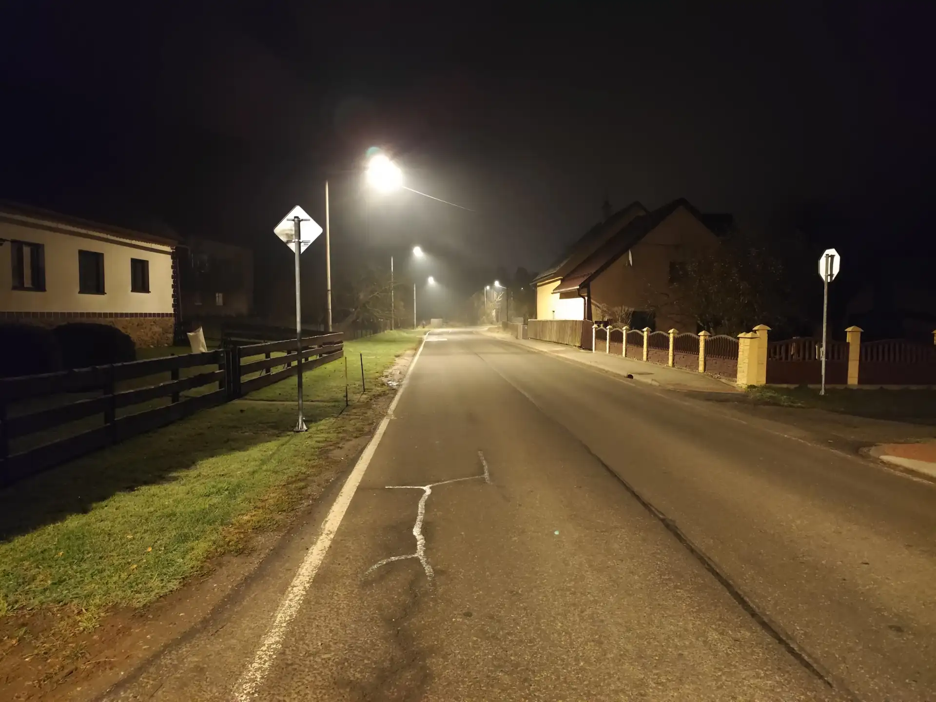 Průhled dlouhou osvětlenou ulicí v noci